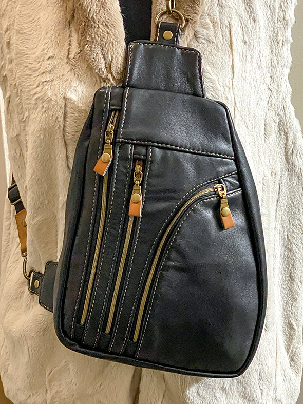 Handmade crossbody bag made from upcycled black leather, featuring three exterior zippered pockets for phone, wallet, and everyday essentials, adjustable crossbody strap, and a bright, eye-catching interior