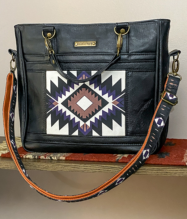 Handmade small carry tote with shoulder strap, made from upcycled black leather with a Native American–inspired tribal pattern, brass accents, and matching patterned shoulder strap, designed as a one-of-a-kind everyday bag